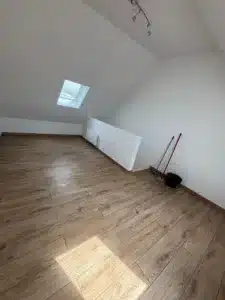 Pièce mansardée terminée avec parquet clair et fenêtre de toit