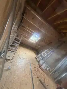 Combles en cours d’aménagement avec plaques de plâtre et échelles