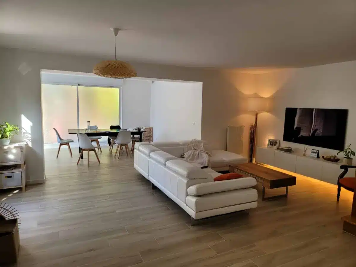 Salon après aménagement intérieur Salon lumineux avec parquet, canapé blanc et grande baie vitrée