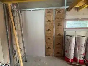 Isolant posé contre un mur des combles, rouleaux d’isolant en attente