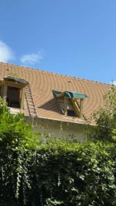Lucarnes dans une toiture en tuiles au-dessus d’une haie